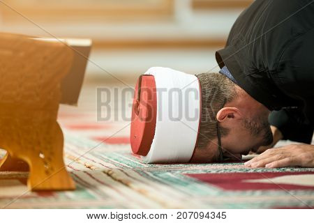 Young Imam praying inside of beautiful mosque.