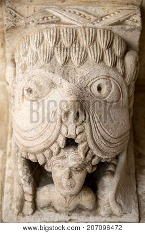 MONTMAJOUR FRANCE - JUNE 26 2017: Monster or Tarasque Devouring a Sinner c12th Romanesque Carving in the Cloisters Montmajour Abbey near Arles Provence France