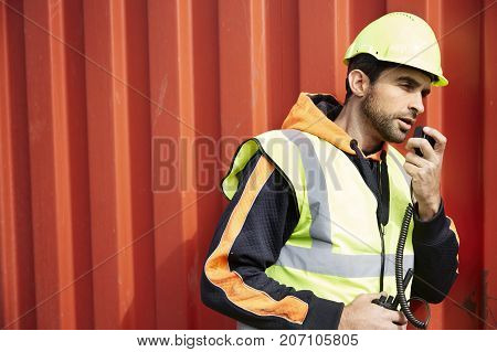 Docker guy in hard hat using walkie talkie side view