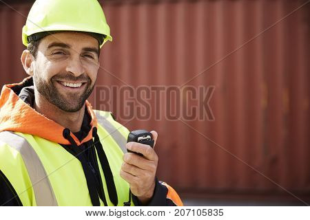 Smiling docker guy in hardhat with radio portrait