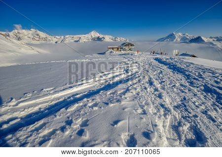 Ski lift station in mountains at winter. Alpine winter mountain landscape. French Alps covered with snow in sunny day. Val-d'Isere, Alps, France