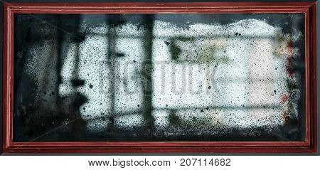 Reflection in old vintage mirror with scratches and dust.