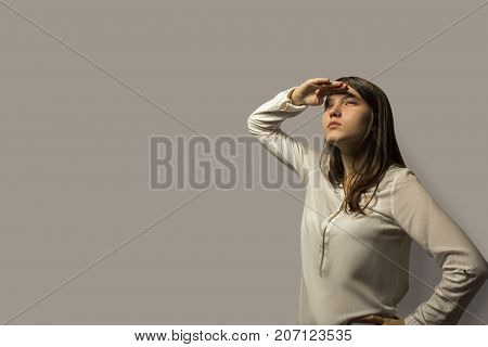 Portrait Of A Young Beautiful Student Girl With Long Hair. Holding Her Hand Above Her Eyes, As If Sh