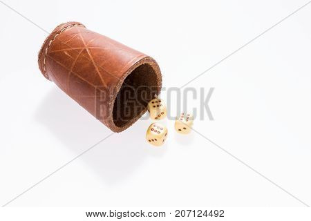 Three dice with leather cup on white background