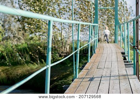 Old wooden pendant bridge with a child, The Urals village, Russia