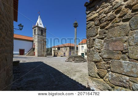 View of the central square of the historic village of Castelo Mendo in Portugal with a church and pillory; Concept for travel in Portugal