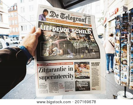 PARIS FRANCE - OCT 3 2017: Man buying De Telegraaf newspaper with socking title and photo at press kiosk about the 2017 Las Vegas Strip shooting in United States with about 60 fatalities and 527 injuries