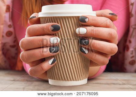 Manicured hands holding cardboard cup. Female hands with perfect manicure holding disposable cup of coffee. Time for beauty and relax.