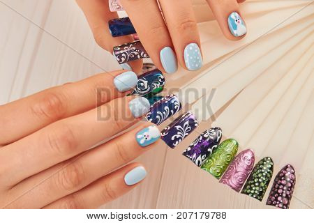 Beautiful manicure and nail art samples. Female hands with perfect winter manicure and fashion samples of nail design close up. Nail beauty salon.