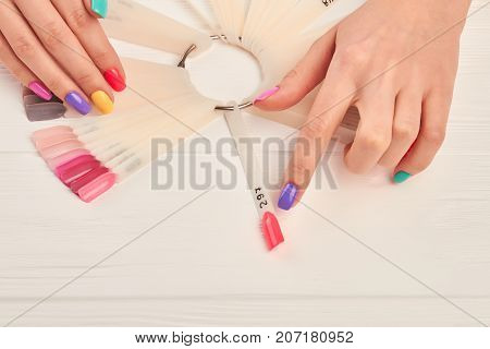 Female finger choosing nail color. Woman index finger indicating on pink color of nail color sample. Summer colors nail polish palette and female hands.