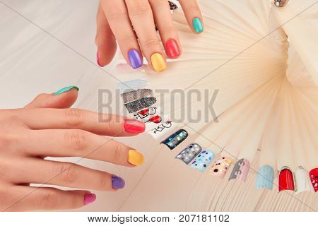 Stylish manicure and nail art samples. Beautiful hands with pastel summer manicure. Nail art design palette and manicured hands close up. Nail art fashion design samples.