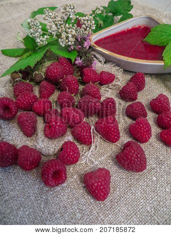 scattered on the table ripe fresh berries of raspberries along with jam.