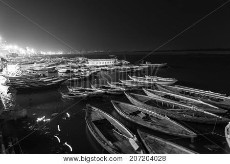 VARANASI INDIA - MARCH 13 2016: Long exposition black and white picture at night of moving boats at Dashashwamedh Ghat in Ganges River after religious Ganga Aarti ritual in Varanasi India.