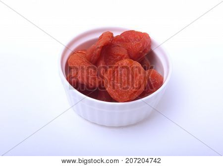 Delicious dried organic apricots on bowl isolated over white background