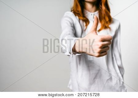 red-haired girl in white shirt shows thumbs up, isolated