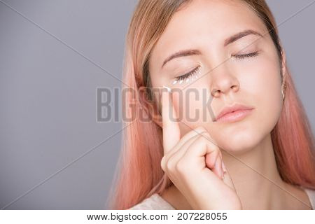 Eye cream treatment. Girl applying cream around her eye