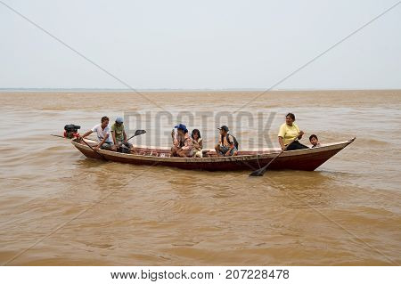 Boca de valeria Brazil - December 03 2015: people rowing in boat on brown water surface on grey sky. Travel and travelling concept.