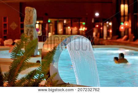 Relaxation pool in spa with waterfall, inside