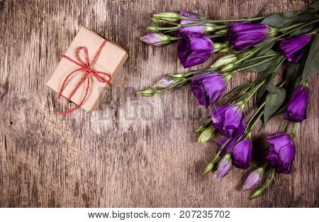 A small gift box and flowers on an old wooden background. Copy space