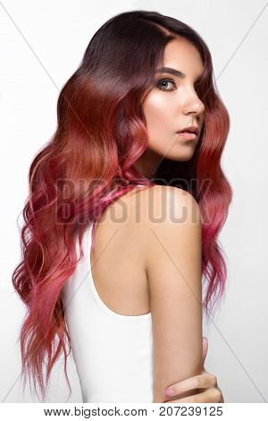 Beautiful pink-haired girl in move with a perfectly curls hair, and classic make-up. Beauty face. Picture taken in the studio.