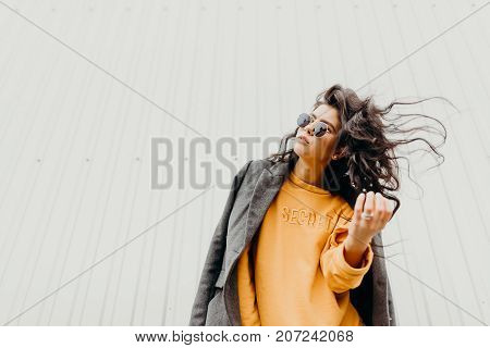 Portrait Of Stylish Modern Young Curly Woman In Coat Sunglasses. She Smile At Camera On The Street A