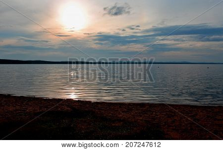 Hazy Sun Over The Lake Shines Through The Gray Clouds