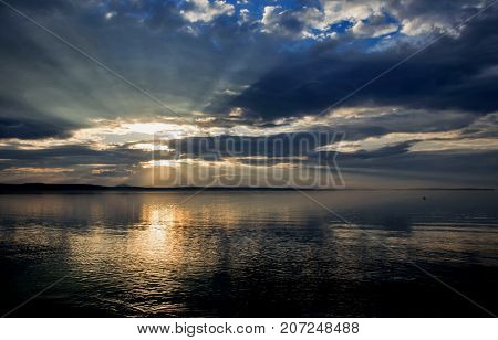 Sun Over The Lake Shines Through The Gray Clouds