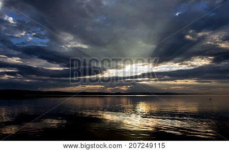 Sun Over The Lake Shines Through The Gray Clouds