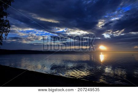 Sunlight Breaking Through Gray Clouds Over The Lake