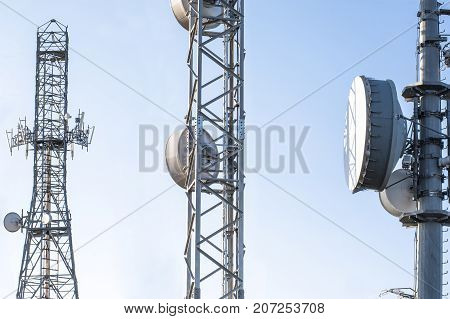 Broadcast relay station antennas at rising. Telecommunications towers with blue clear sky.