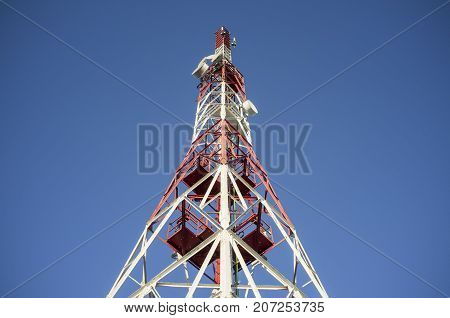 Broadcast relay station antenna over blue sky. Low angle view