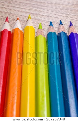 Different colored pencils photo with space for text. Seven pencils of rainbow colors lie on the table. Copyspace. Back to school. Wooden background.