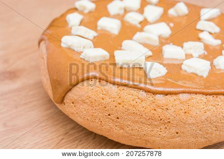 Homemade baking. Pie covered with caramel. Pieces of white porous chocolate. Sweets. Dessert. Tasty food.