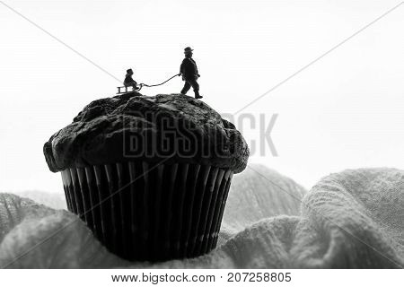 miniature man pulls child on a sled