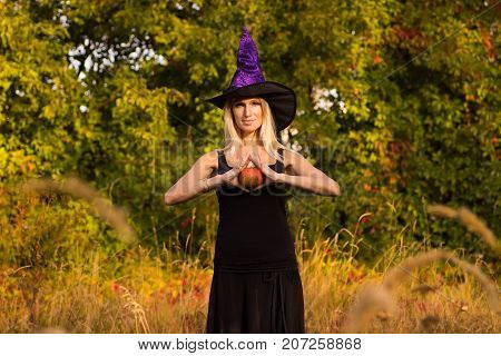 Active girl in Halloween costume practicing yoga positions with pumpkins in her hands