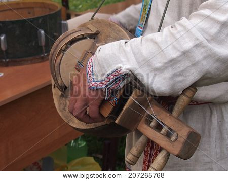 The musician in a holshchevy shirt plays on a psaltery