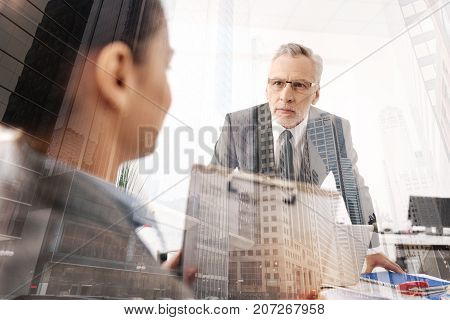 Give vain to your feelings. Strict erious boss leaning on the table and feeling angry with his female office worker
