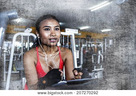 young sexy and sweaty Asian woman training hard at gym using elliptical pedaling machine gear in intense workout exercise wearing sport top and gloves in fitness and healthy lifestyle concept