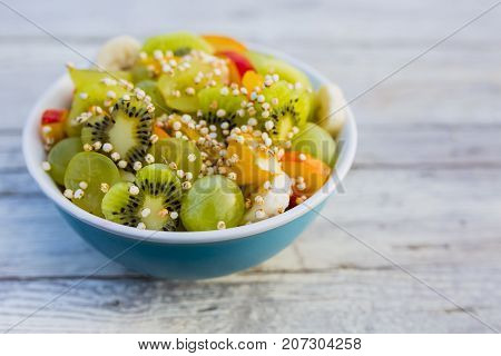 Delicious fruit salad in a bowl on a wooden table.