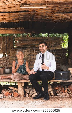 Male Doctor listening heart beat and breathing of Elderly Woman with Stethoscope with First Aid Medical Box.Community Health and Development Hospital In Remote Areas Development Fund Concept.