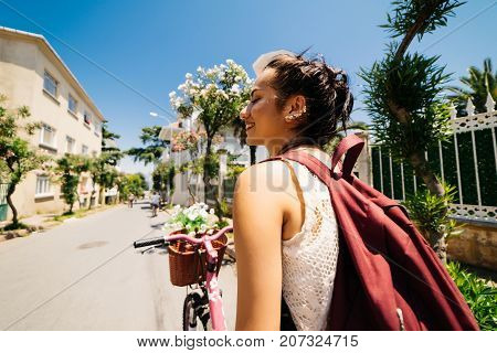 Smiling eastern girl on vintage bicycle with backet of flowers