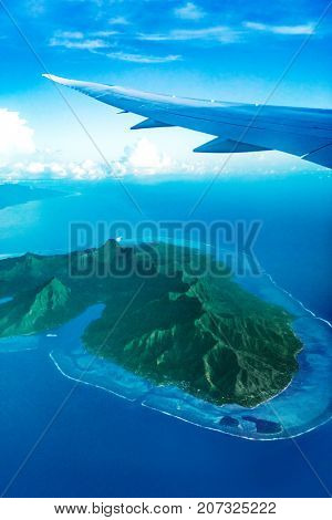 View from plane window flying over Moorea island, Tahiti, French Polynesia. Exotic luxury vacation flight travel. Tropical paradise destination.