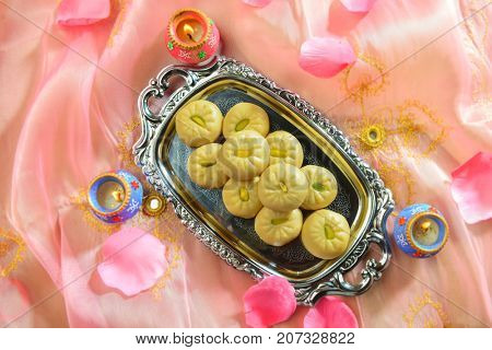 'Pedha' an Indian sweet made from condensed milk. A festive set up with traditional lamps.