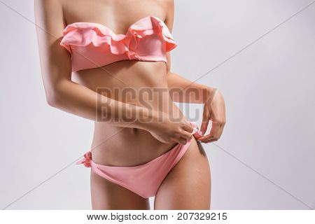 Beautiful young woman in bikini on light background