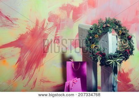 Christmas fir tree wreath shopping bag on wooden chair. Decoration and present package on colorful background. New year gift and decor. Xmas party celebration. Winter holiday and vacation copy space