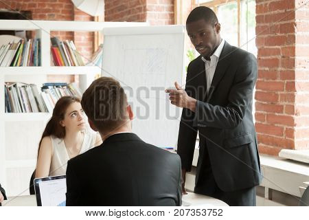 African American employee behaving rudely during briefing meeting. Disgruntled corporate worker expressing frustration to his coworkers. Angry businessman unhappy with unproductive meeting result.