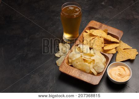Beer In Glasses Closeup On The Concrete Table. Beer And Snacks Are Chips And Nachos In Wooden Bowl W