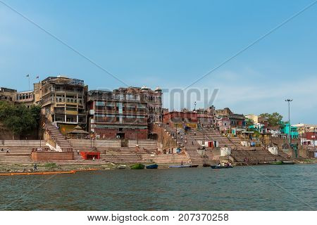 VARANASI INDIA - MARCH 14 2016: Wide angle picture of riverbank with many stairs of the Ghat in front of Ganges River in the city of Varanasi in India