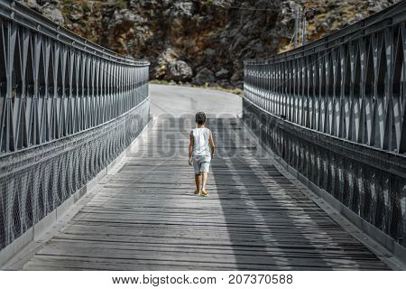 Little boy alone walking on a bridge, Aradena, Crete, Greece on August 20, 2017.