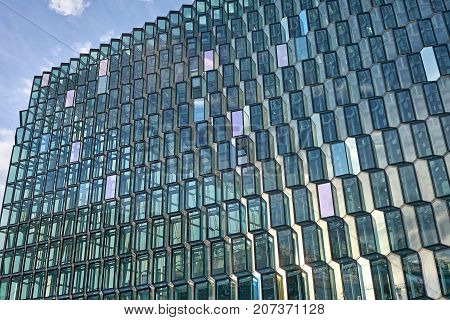 Incredible patterned glass wall of Harpa Hall on blue sky background in Reykjavik in Iceland. Sun shines onto it. Horizontal.